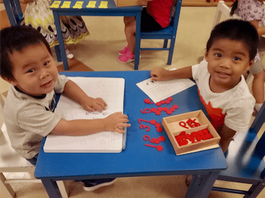 Two young boys learning with red number blocks.