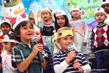 Children in a Christmas play singing into microphones.