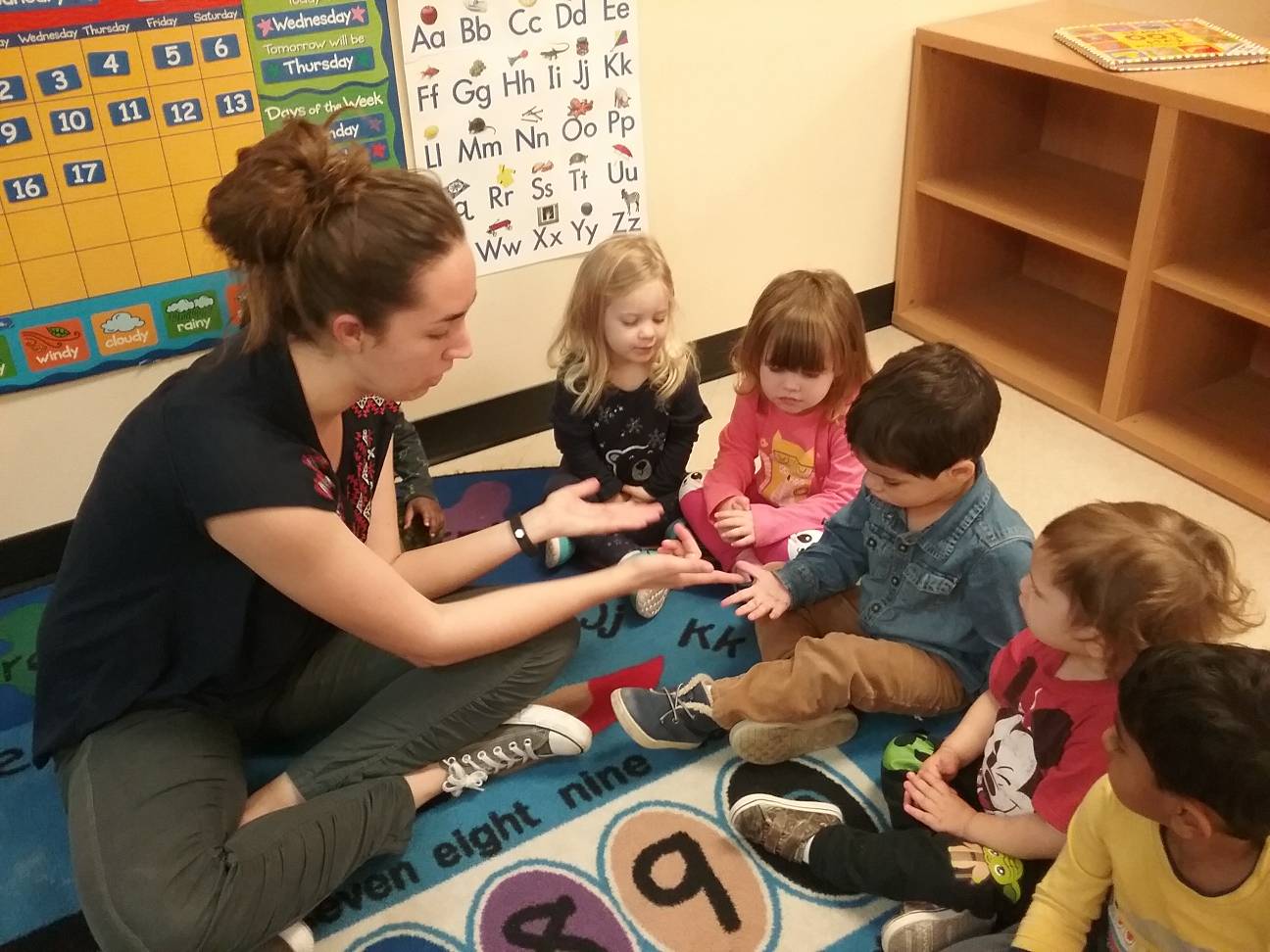 Teacher and children playing on the floor.