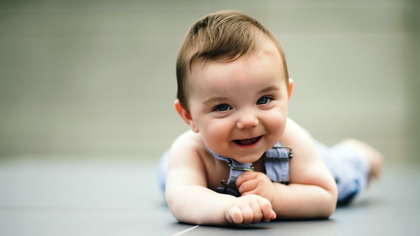 Smiling baby boy wearing overalls.