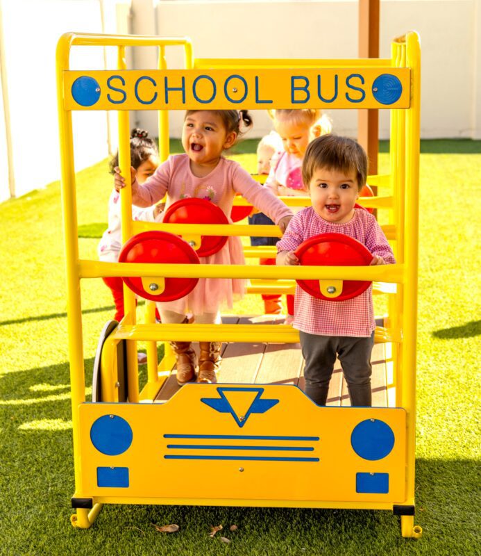 Preschoolers playing on a yellow school bus.