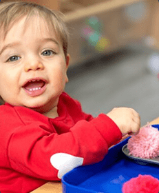 Smiling infant playing with Montessori toys at Inspire Kids Montessori preschool