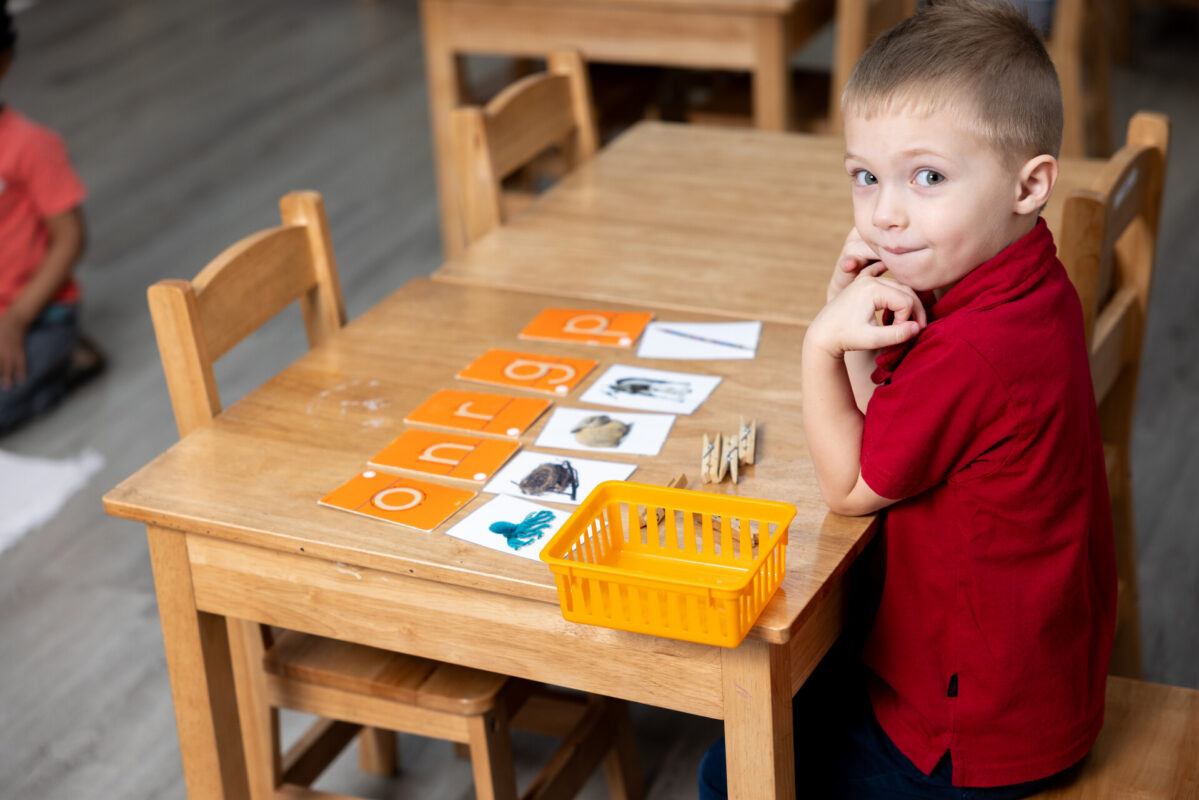 Toddler working independently with Montessori language materials in an Inspire Kids Montessori classroom
